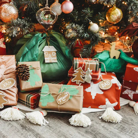 A stack of presents sit under a tree with hand painted paper.