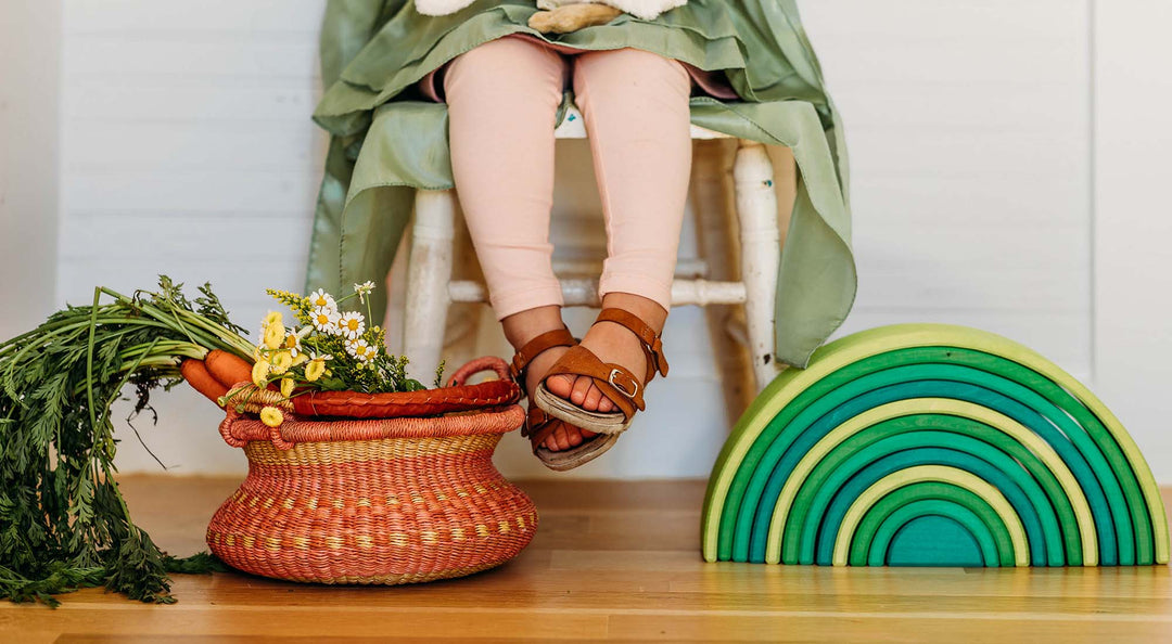 A young. girl is sitting in a spring themed setting with a handcrafted bolga basket.