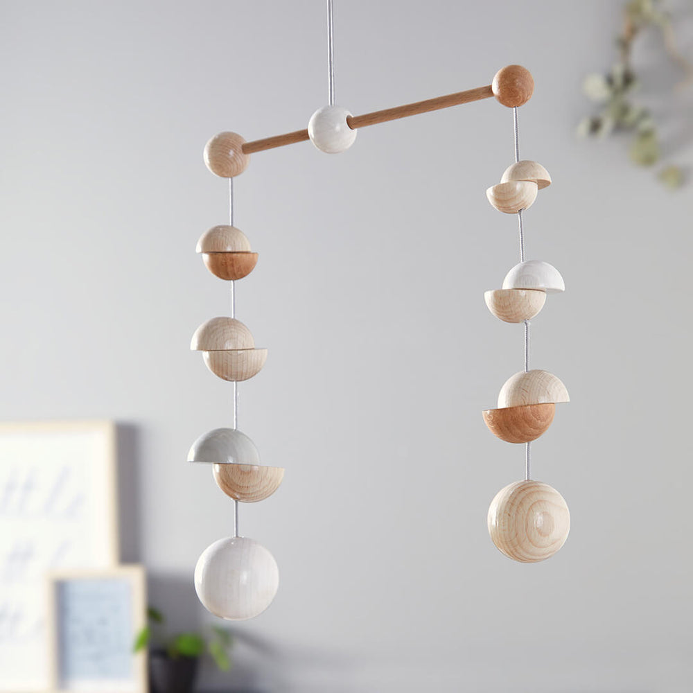 Wooden Mobile Dots featuring a mix of round and half-sphere shapes in natural and white finishes, suspended against a soft backdrop.