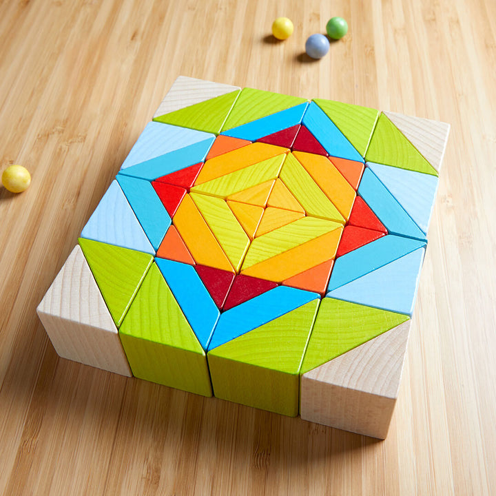 A colorful, geometric wooden puzzle arranged in a star pattern, with small round candies scattered nearby.