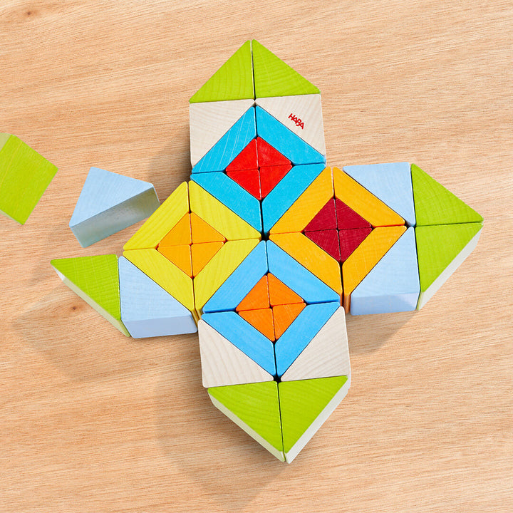 Colorful wooden building blocks arranged in a geometric pattern, featuring triangles and diamonds on a wooden surface.