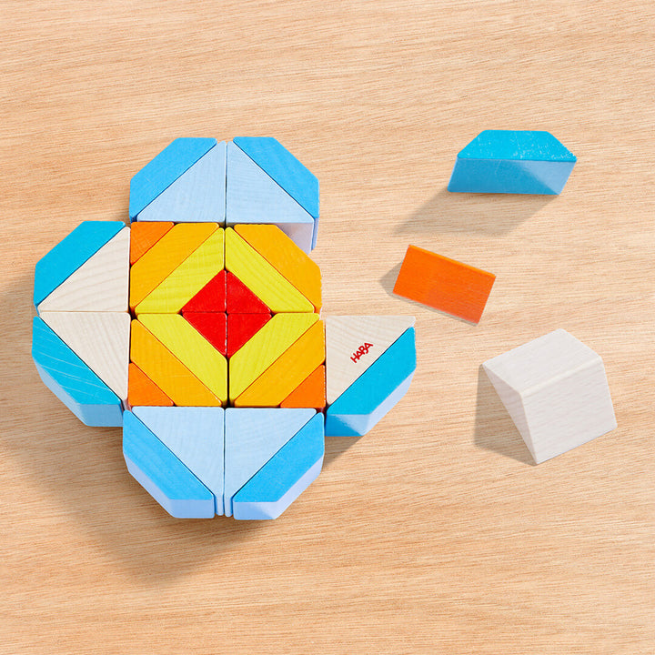 Colorful geometric blocks arranged in a flower shape, with a few loose blocks in orange, light blue, and white nearby.