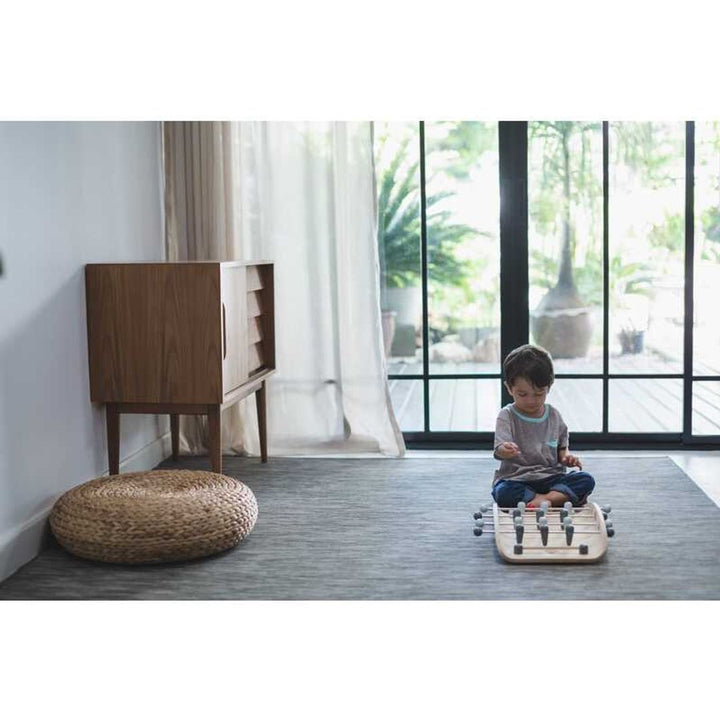 Child playing with PlanToys - Wooden Tabletop Soccer Game on floor in living room