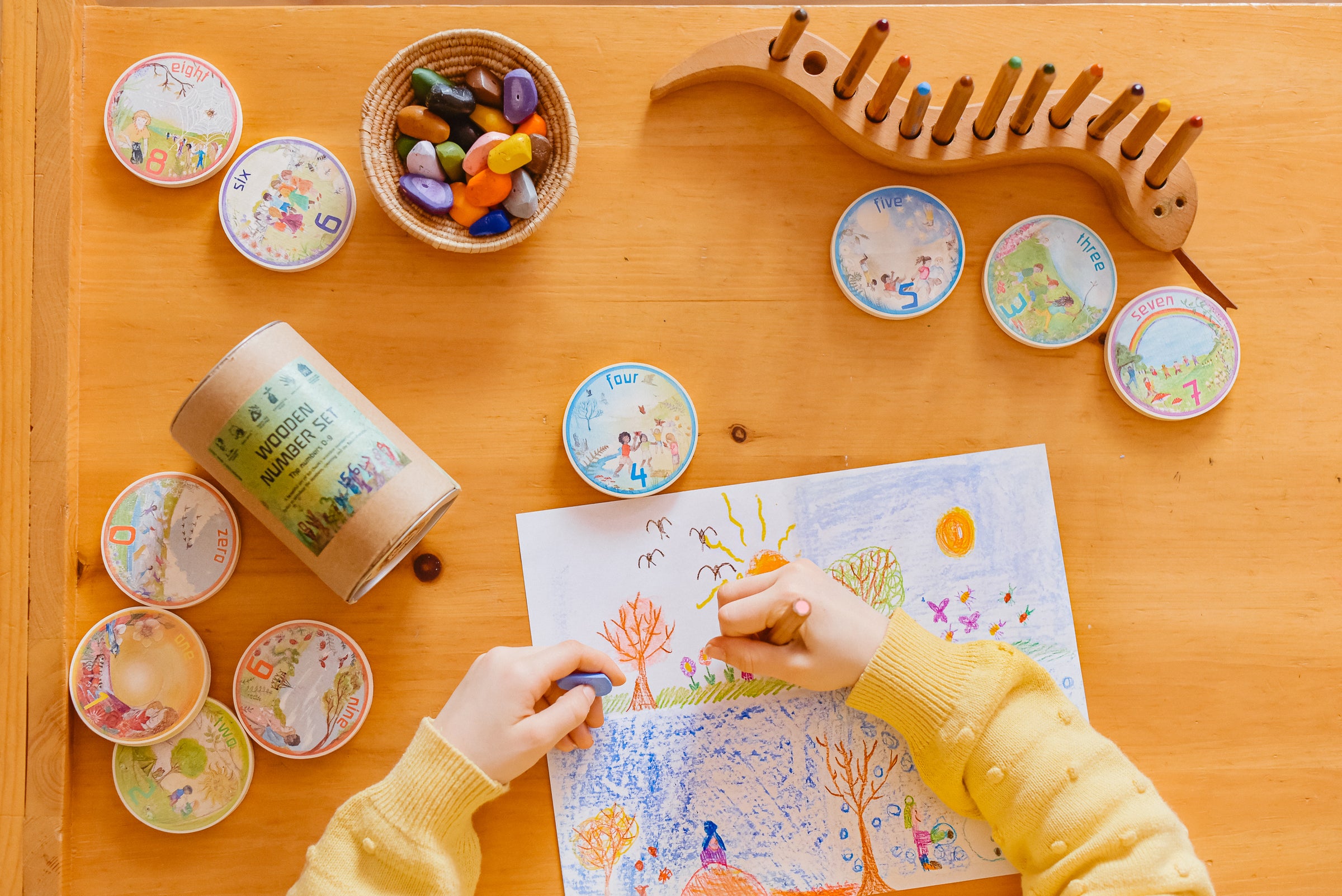 Child drawing with Wilded family wooden number set scattered on table