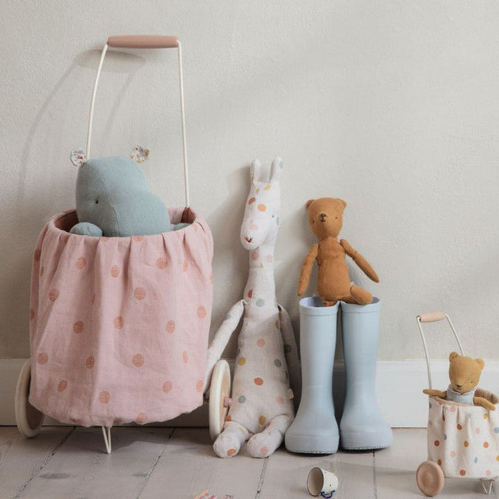 A pink polkadotted Maileg trolley with stuffed animals inside it and next to it.