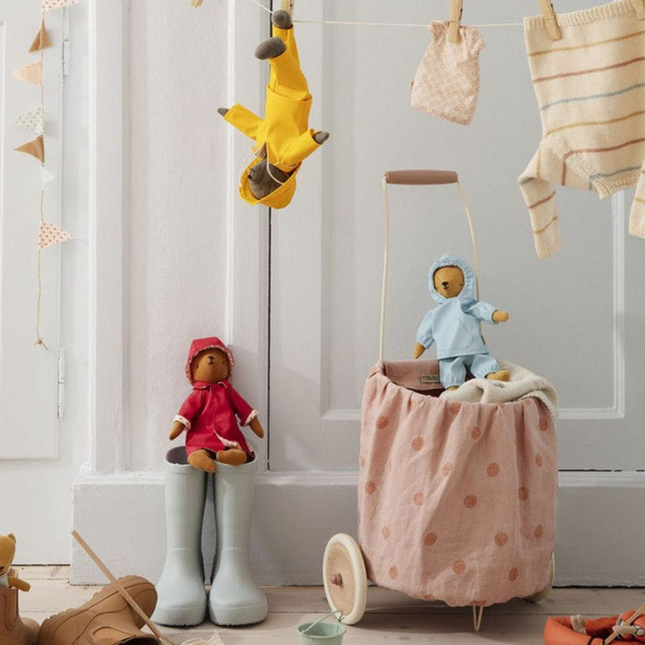 A pink polkadotted Maileg trolley with stuffed animals inside it and next to it.