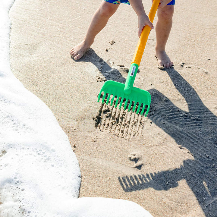 Child playing on the beach with Spielstabil Garden Rake in the sand