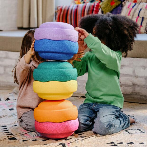 Two children stack and nest Stapelstein Stepping Stones into a balancing tower.