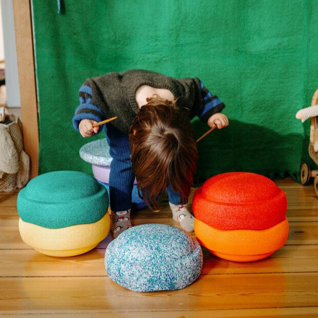 A child puts on a show with the Stapelstein stepping stones fashioned as a drum set and stool.