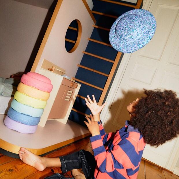 A child tosses the Super Cool Stapelstein balance board into the air.