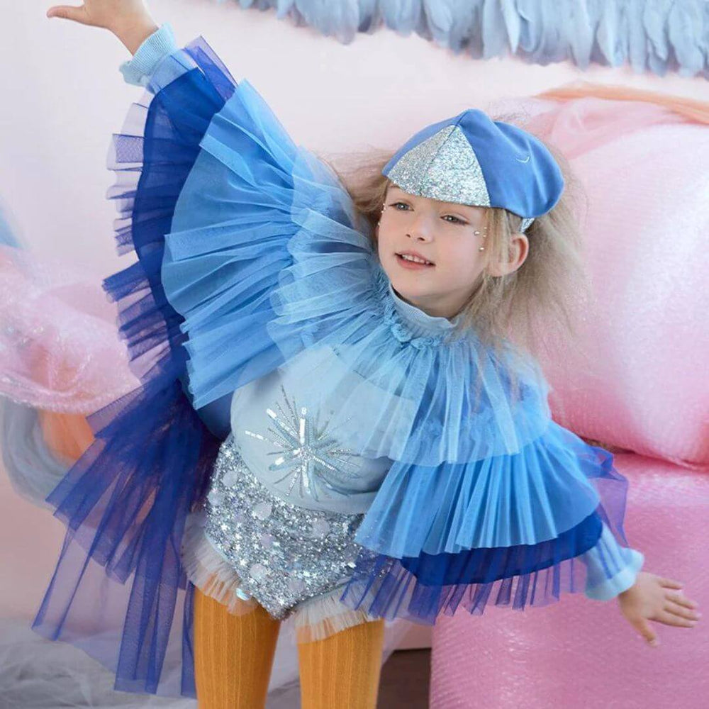 A child pretends to fly in the blue velvet bird costume from Meri Meri.