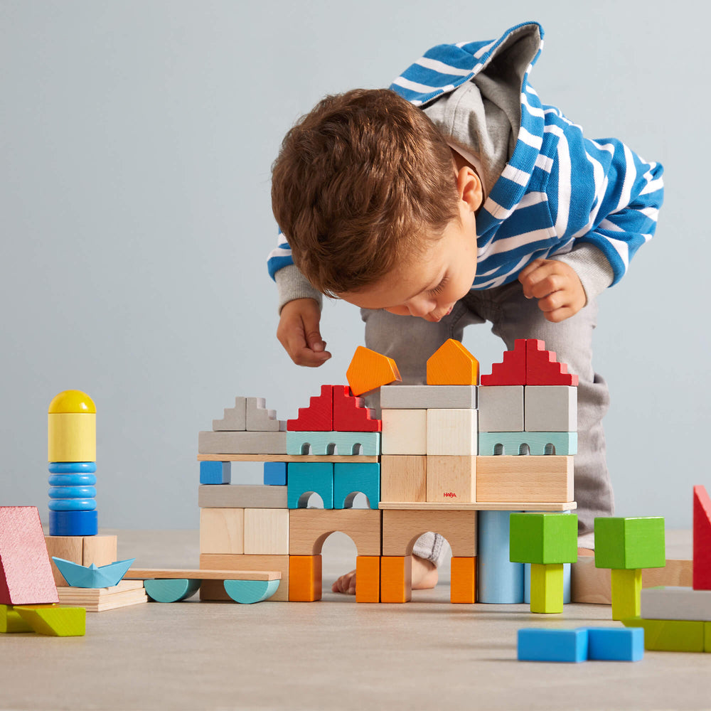 Young child bending over a constructed castle of colored building blocks