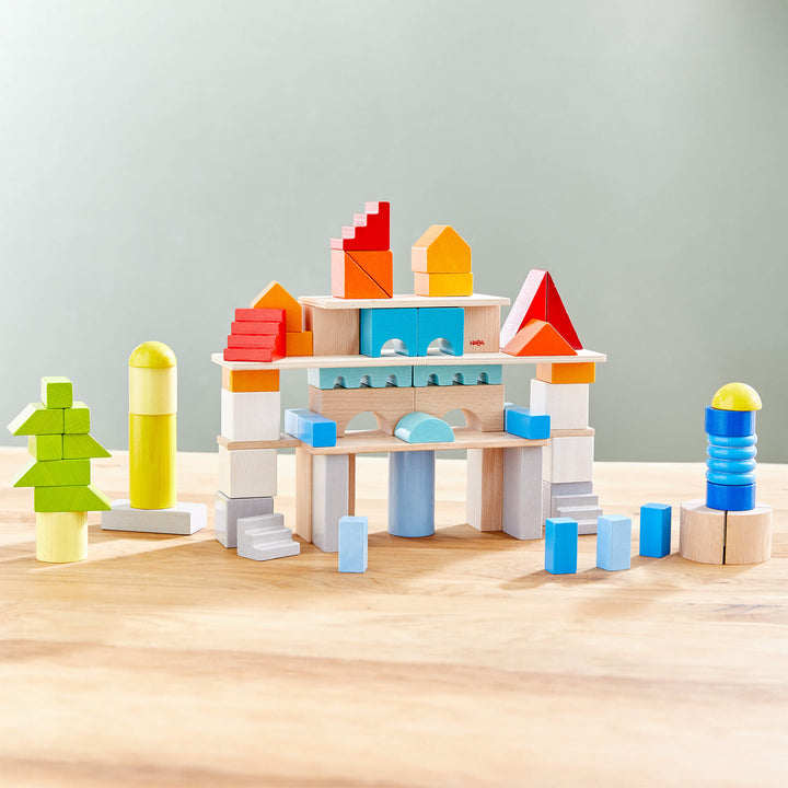 A colorful wooden block structure featuring various shapes, including triangles, circles, and rectangles, on a wooden surface.