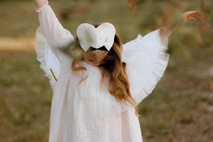 Child wearing Swan Costume with headpiece with her arms raised