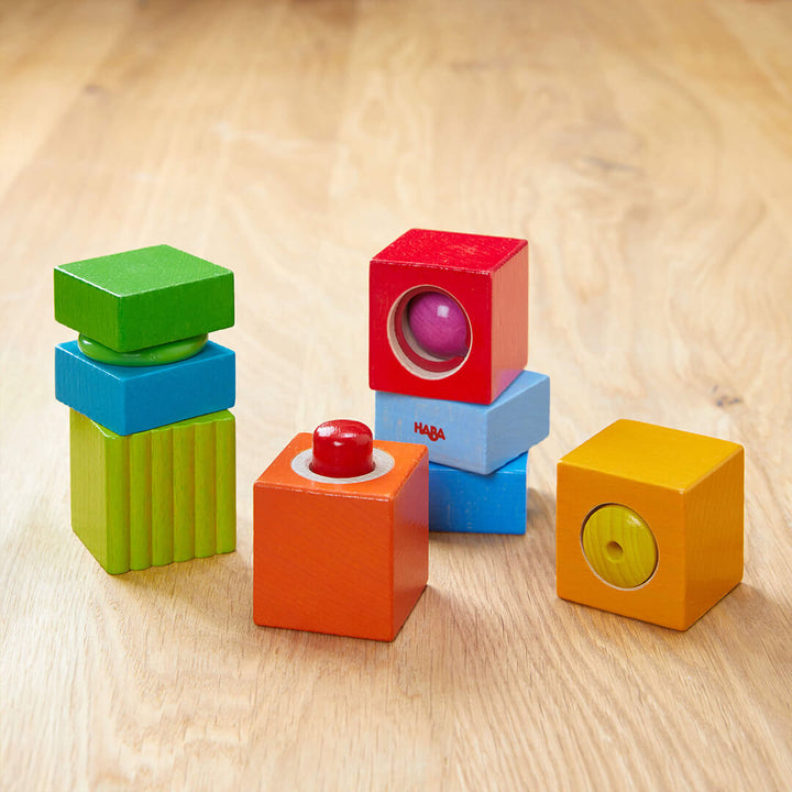 A variety of colorful wooden blocks in different shapes and sizes, featuring holes, textures, and bright colors. on a wood table.