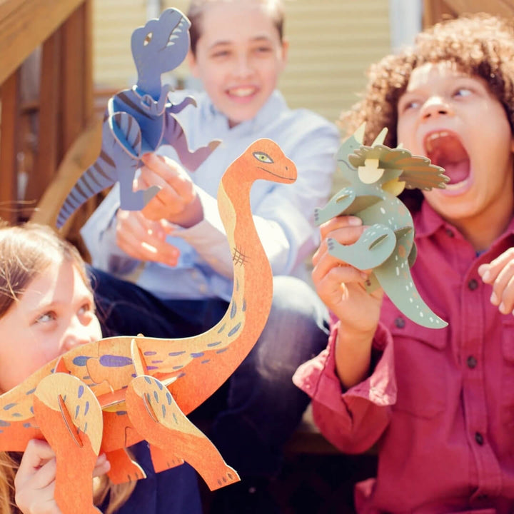 Children holding their completed art projects from the Dinosaur World multi-activity craft kit from Djeco.