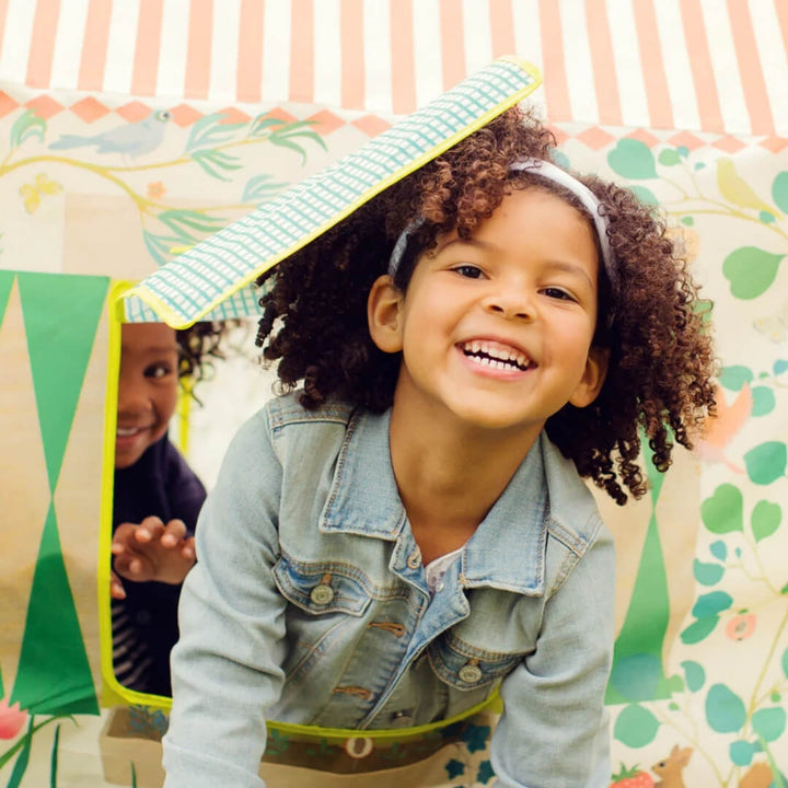 A child leans out of the window of the Garden House Play Tent.