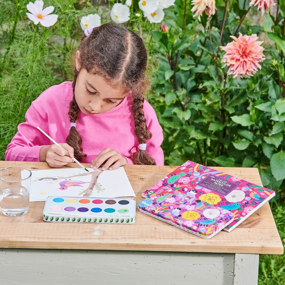 A girl paints with the eeboo Birds in Fuschia watercolor paint set.