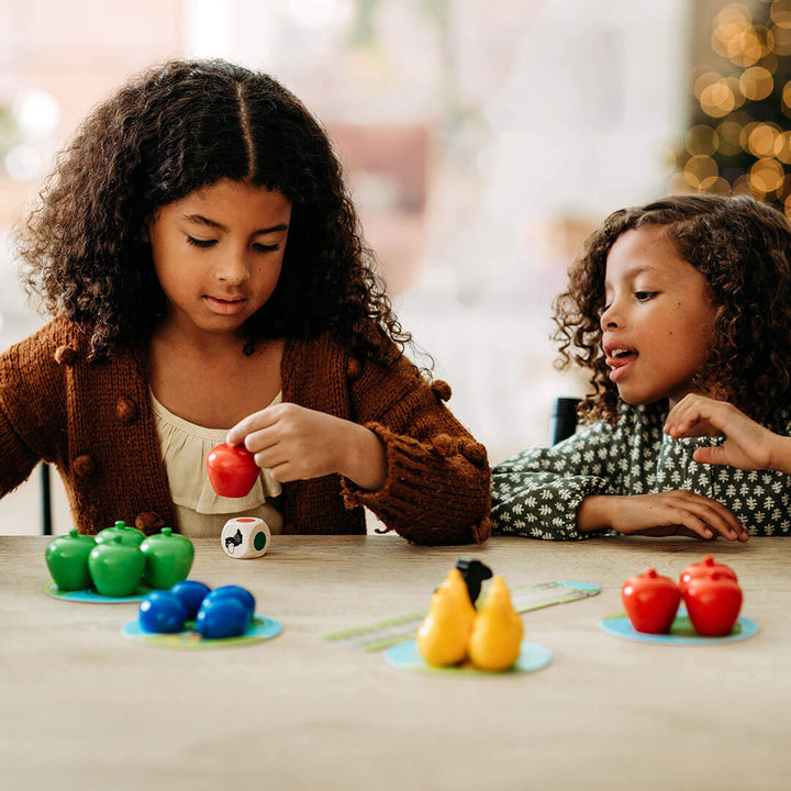 Two young girls play together at a table, engaged with colorful fruit toys in various shapes from My Very First Games - First Orchard