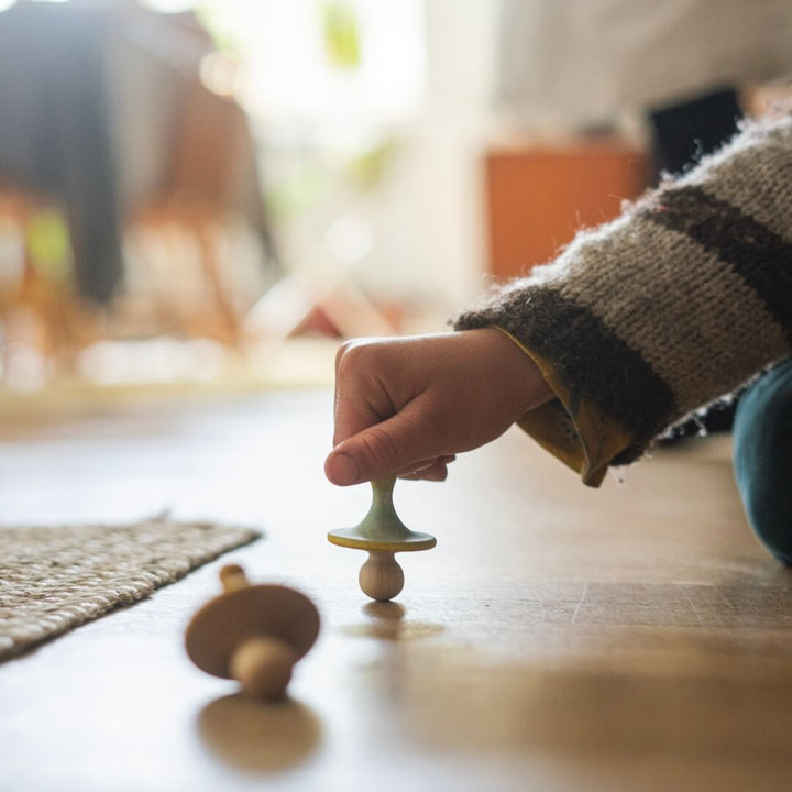 A child's hand spinning the tops from the 2024 Grapat Advent Calendar.