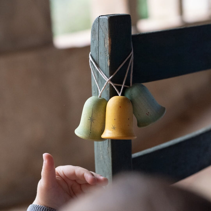 Grapat Jingle Joy Bells wooden ornaments hanging on a wooden chair.