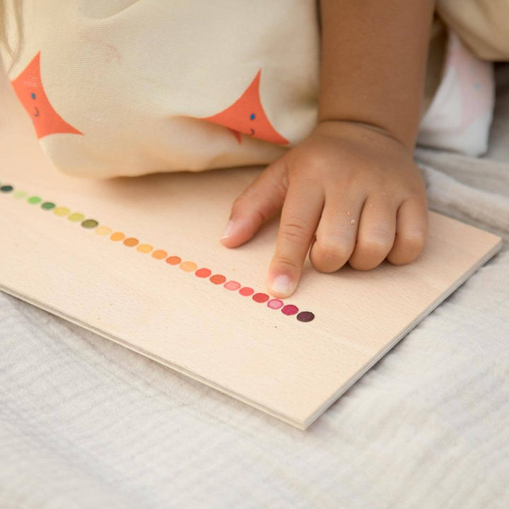 Child pointing to color on wooden tray