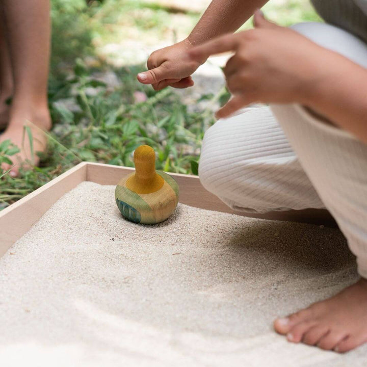 Child playing outdoors with Grapat Flowing Yellow Bird – Hand-Painted Wooden Toy for Open-Ended Play