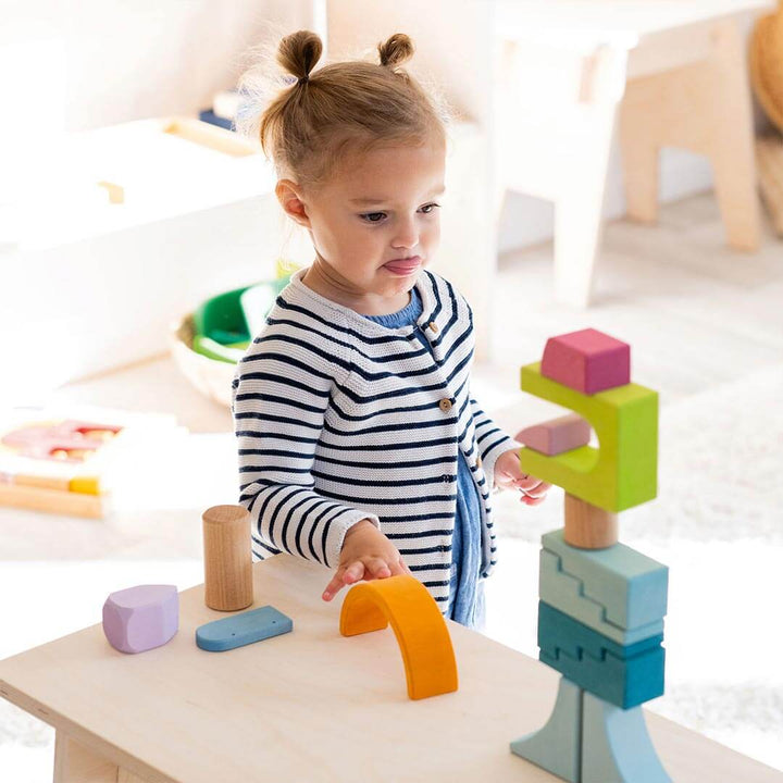 Child playing with Grimm's Wooden Building World Cloud Play Set