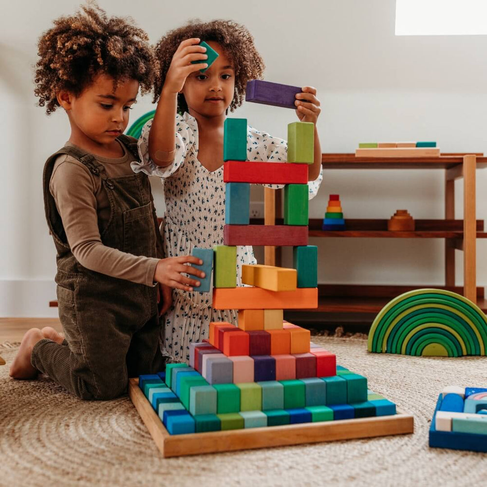 Two children building with the Large Stepped Pyramid from Grimm's Wooden Toys.