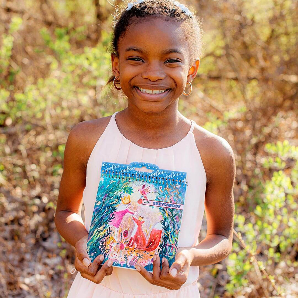 Girl smiling and holding the Square Sketchbook