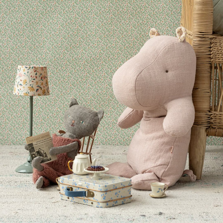 Maileg Light Rose Medium Hippo next to a stuffed cat and toy tea set.