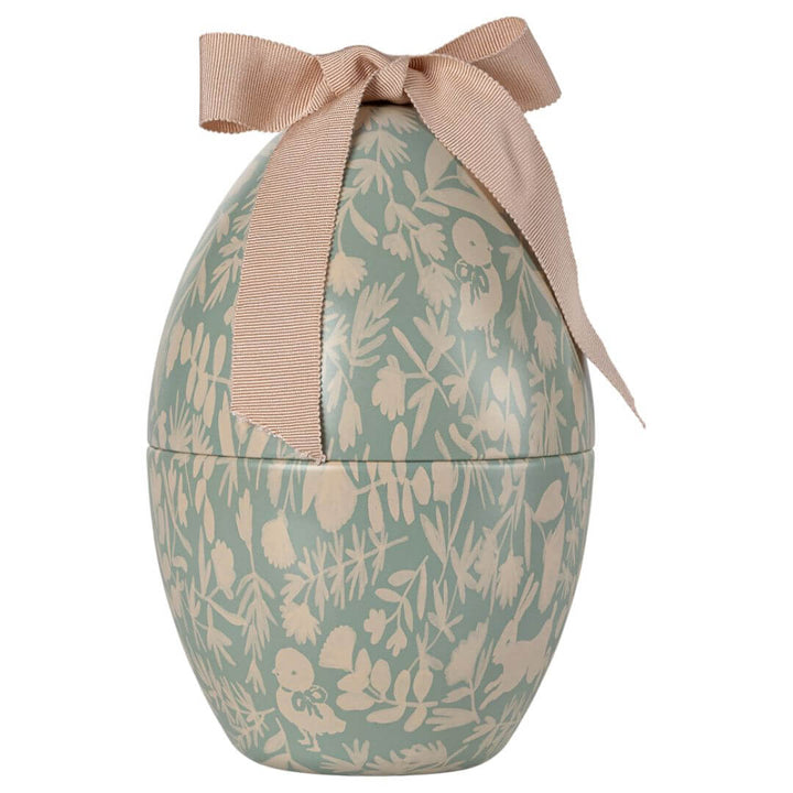 A blue and cream colored metal egg with a Maileg print and ribbon on top.