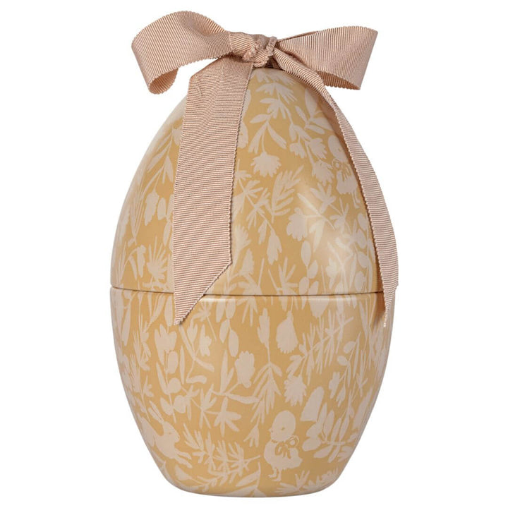 A yellow and cream colored metal egg with a Maileg print and ribbon on top.