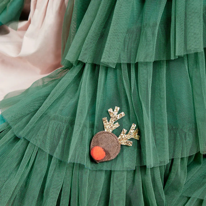 Up close detail of the green tule cape with a reindeer ornament made from brown felt, a red pom pom and golden glittery antlers.