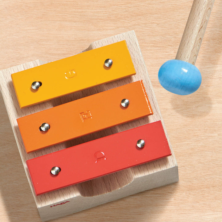 Metallophone and mallet on wooden background