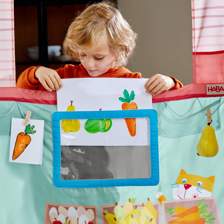 Kid inserting sign into HABA Hanging Doorway Play Store