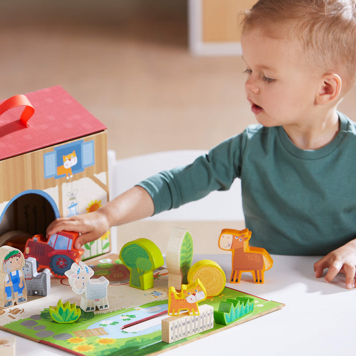 Young boy playing wooden tractor into farm