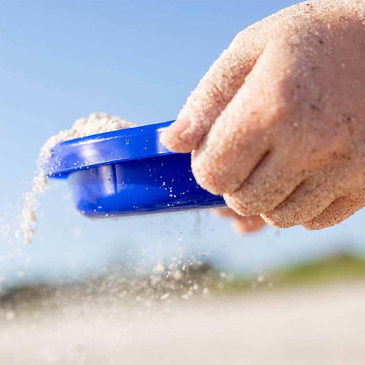 A close up of a blue sand sieve in child's hands