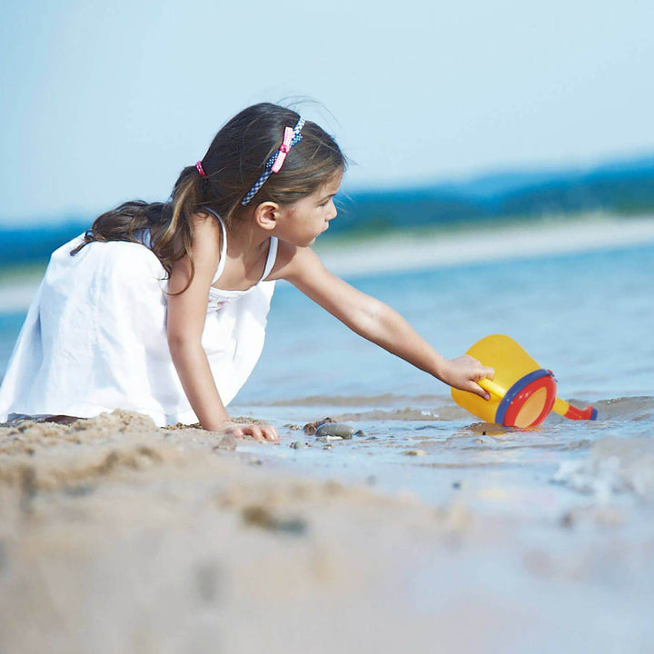 Child scooping water from the ocean with Spielstabil Watering Can