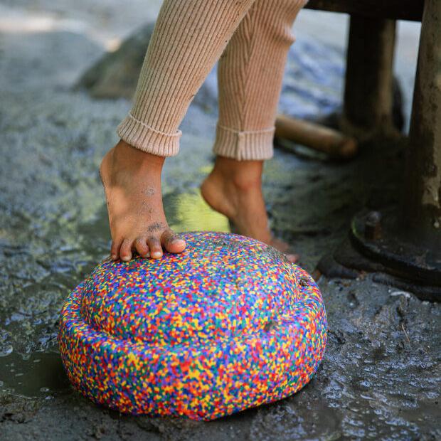 A child's foot stepping on a Stapelstein original confetti stepping stone.