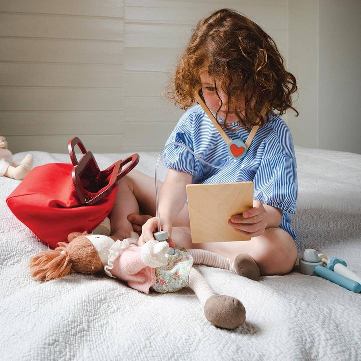 Kid using toy stethoscope and doctor's bag from Tender Leaf Toys Doctor's Bag Wooden Play Set