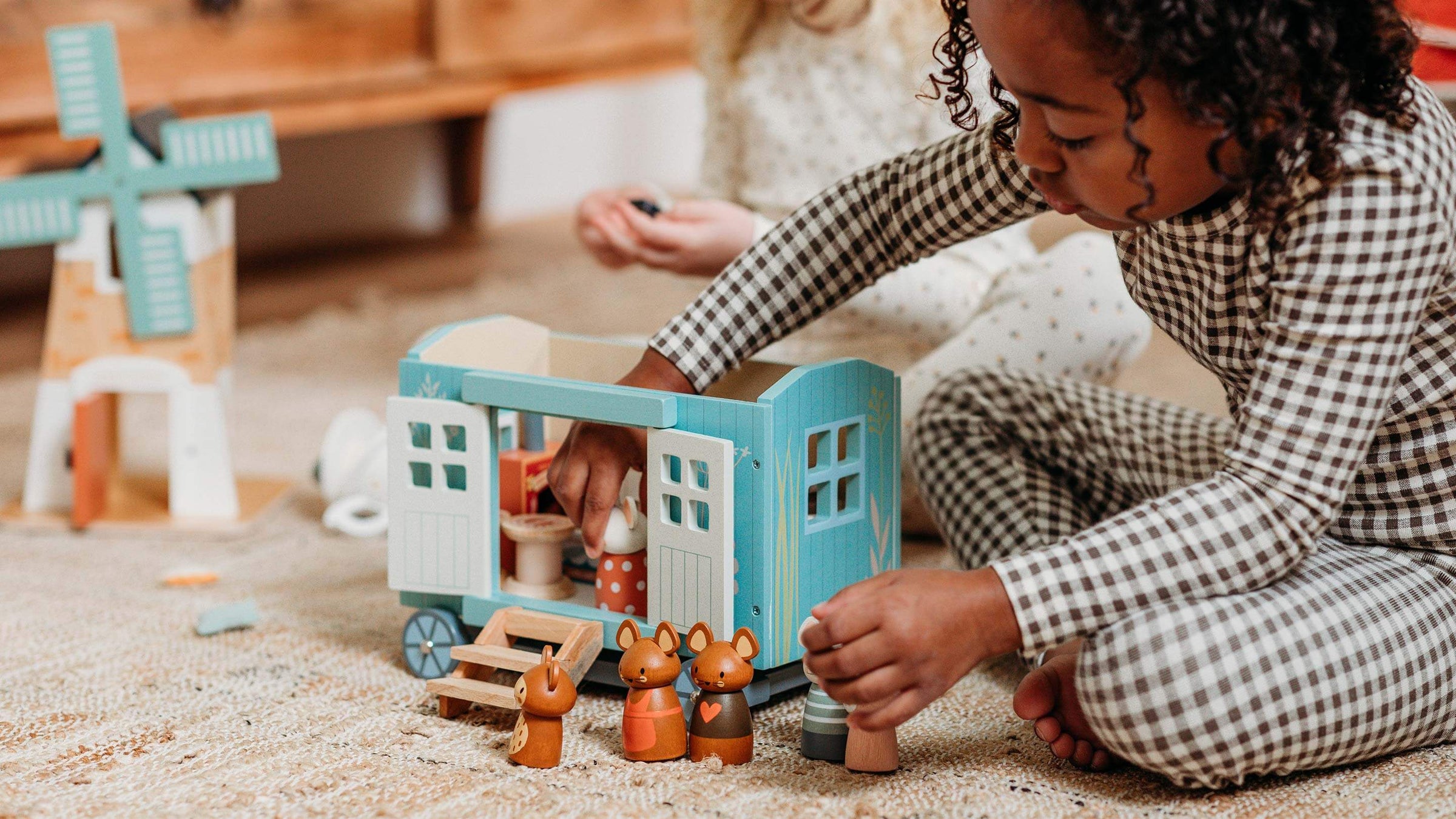 Child playing with blue wooden carriage and mice people by Tender Leaf Toys