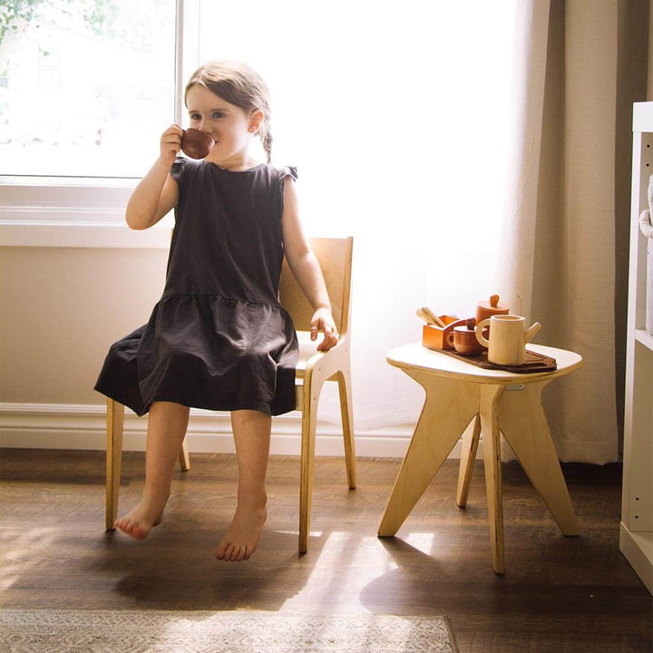 Child sitting on Child's Wooden Chair in living room