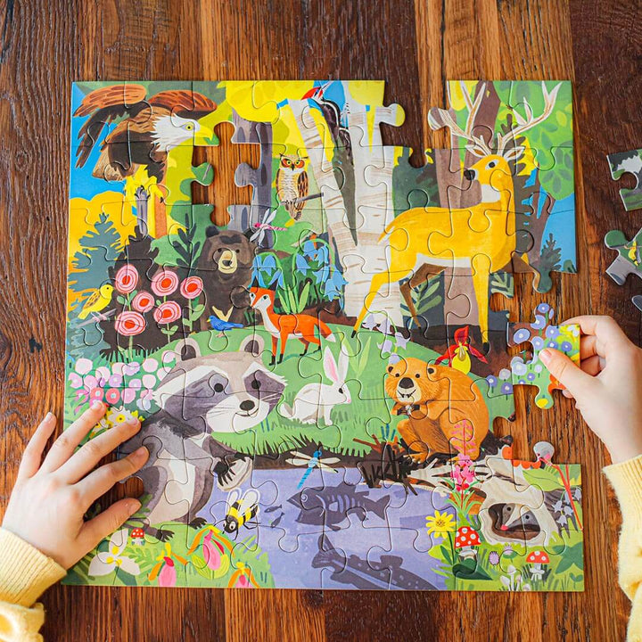 Child's hands placing a puzzle piece in the Woodland 64 Piece Jigsaw Puzzle