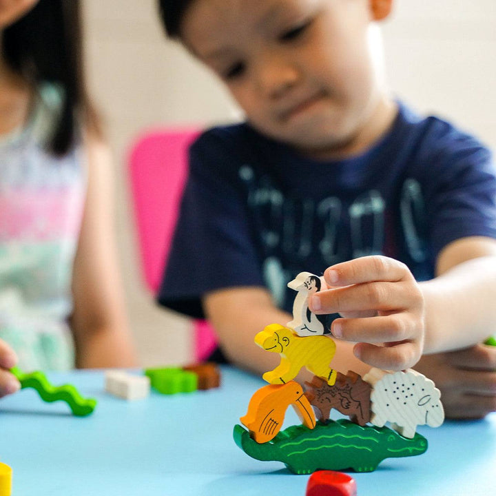 Child shown placing penguin figure on top of other stacked animals