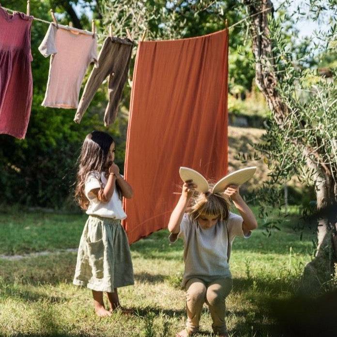 Two children playing outside, with one using 2 petal-shaped pieces from Petal Platform as large rabbit ears