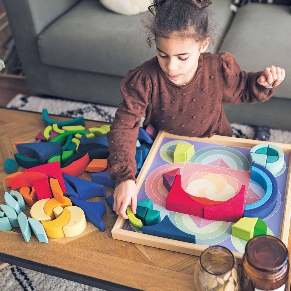 child putting blocks back in wooden frame, following the illustrated colored pattern in the bottom of the tray