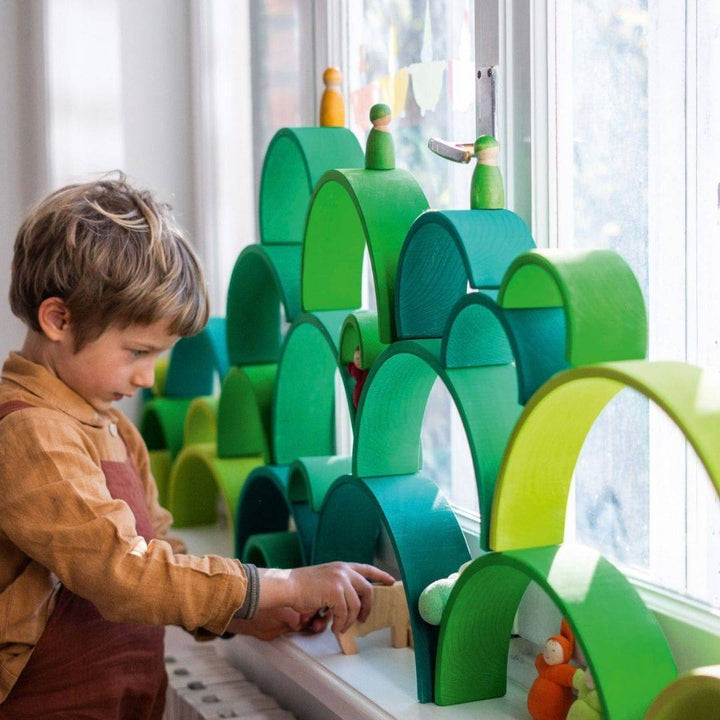 Child playing with Grimm's Wooden Rainbow Forest Green Tunnel